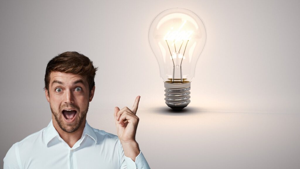Bright smiling man pointing at illuminated light bulb representing innovative social media marketing ideas for businesses.