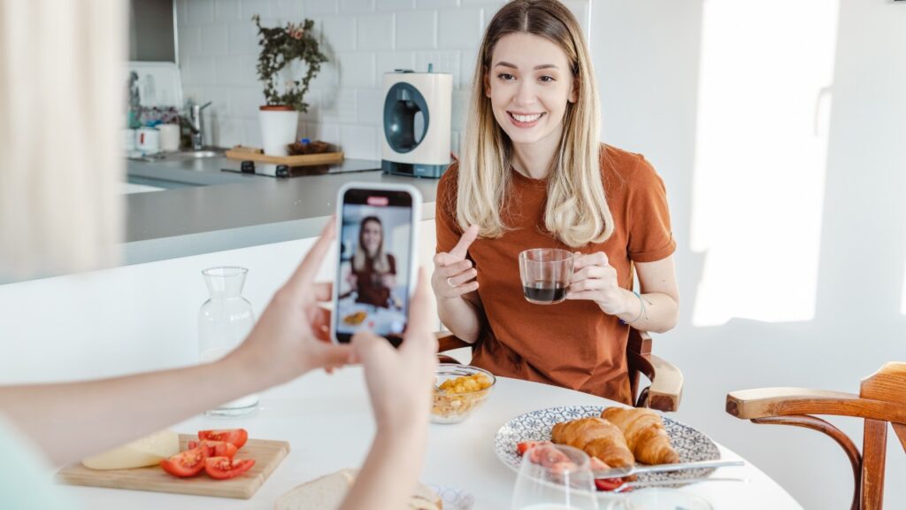 Vibrant social media lifestyle photo of a young woman enjoying breakfast at home, being photographed, ideal for social media marketing, content creation, and influencer branding.